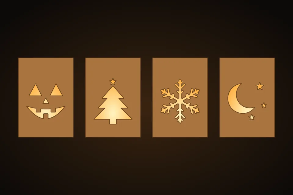 Four lit lantern walls from the Lantern Maker: a jack-o-lantern face, a Christmas tree, a snowflake and a moon with stars cut through wood